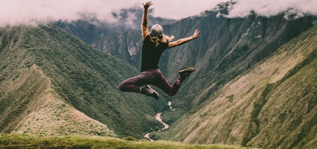 woman jumping on green mountains by Peter Conlan courtesy of Unsplash.